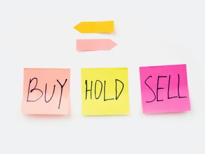 Colorful sticky notes with financial terms 'Buy', 'Hold', and 'Sell' on a clean white backdrop.