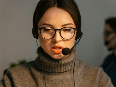 Close-up of a focused call center agent with eyeglasses and headset providing customer support.