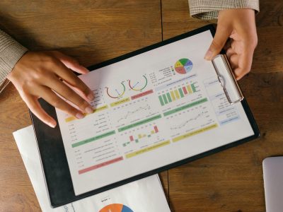 Top view of hands holding a financial report with colorful graphs and charts, ideal for business presentations.